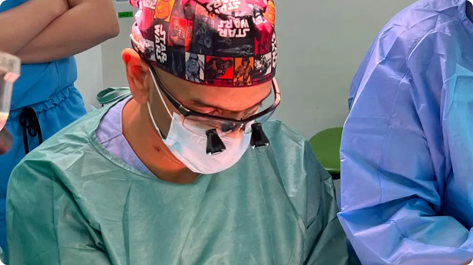 Doctor Juan Carlos Gómez en cirugía con gafas y gorro